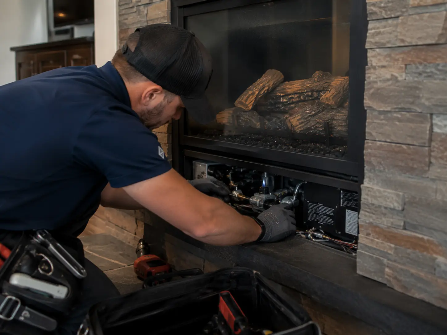 Professional checking burner and ignition area inside a gas fireplace